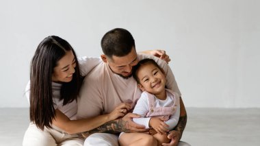 Asyalı ebeveynlerin gri arka planda bebeğe sarıldığı afiş resmi