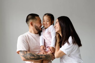 Genç ve mutlu Asyalı anne babalar birbirlerini izliyorlar. Küçük kızlarını Grey 'de izole etmişler.