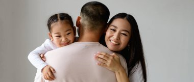 Gülümseyen Asyalı kadın ve bebeğe sarılan çocuğun afiş resmi. Gri yolda izole edilmiş baba.