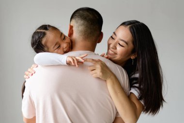 Neşeli Asyalı anne ve kız sarılan babayla oynuyorlar.