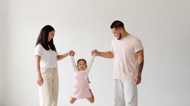 Modern Asyalı ebeveynler neşeli kızlarıyla oynuyorlar. Gri yolda tek başlarına.