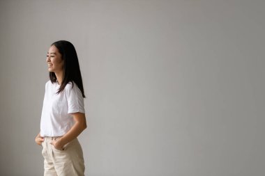 Gri tişörtlü, gülümseyen Asyalı bir kadın.