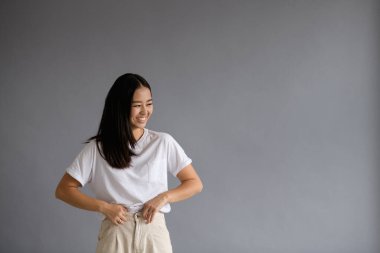 Neşeli esmer Asyalı kadın. Gri pantolonunu düzeltiyor. Fotokopi alanı var.