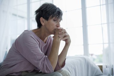 Hüsrana uğramış olgun bir kadın evde yatakta otururken gözlerini kaçırıyor.