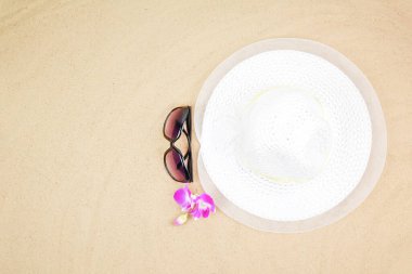 Top view seyahat plaj arka planı konsepti güneş gözlüğü ve kumdaki plaj şapkası..