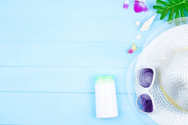 Güneş gözlüklü, plaj şapkalı ve mavi ahşap arka planda aksesuarlı üst görünüm seyahat kavramı.