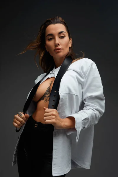 Retrato de una joven sexy desnudándose sobre fondo gris. Modelo femenino quitándose la camisa. —  Fotos de Stock