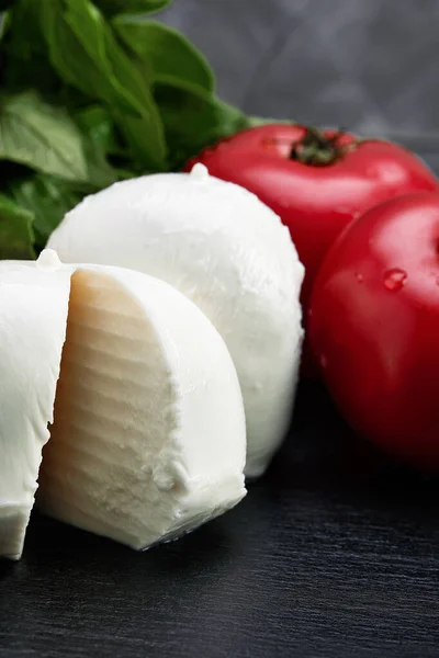 Tomat, basilika blad, mozzarella ost bollar på grå bakgrund. Italiensk kaprissallad ingredienser. — Stockfoto