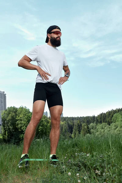 Hombre atlético barbudo haciendo ejercicio en el gimnasio al aire libre en la puesta del sol — Foto de Stock