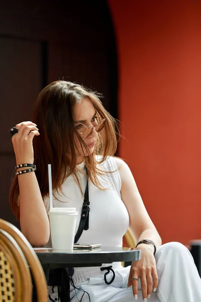 Elegante joven morena belleza teniendo sabrosos refrescos en la cafetería de la calle. — Foto de Stock