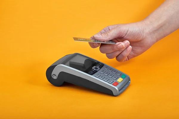 Close-up of payment machine buttons with human hand holding plastic card near by on yellow background — Stock Photo, Image