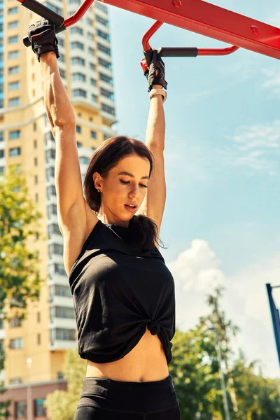 Photo of young european woman on a street workout in sports park on sunny day. Concept of training outdoor.