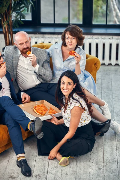 Equipe de negócios feliz comer pizza no escritório.Conceito de negócios, comida, almoço e pessoas. — Fotografia de Stock