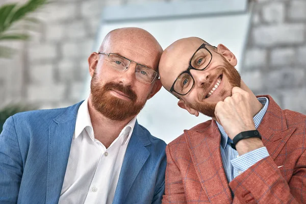 Deux hommes d'affaires souriants regardant la caméra. Des jeunes hommes joyeux portant des vêtements formels posant au bureau. Concept d'entreprise — Photo