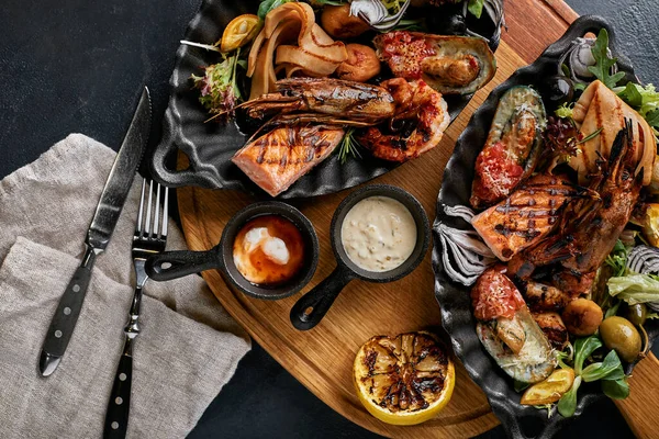 Plato de mariscos a la parrilla. Surtido de deliciosos mariscos a la parrilla con verduras. Bastardos mixtos a la parrilla con salsa de pimienta y verduras. Fondo negro — Foto de Stock