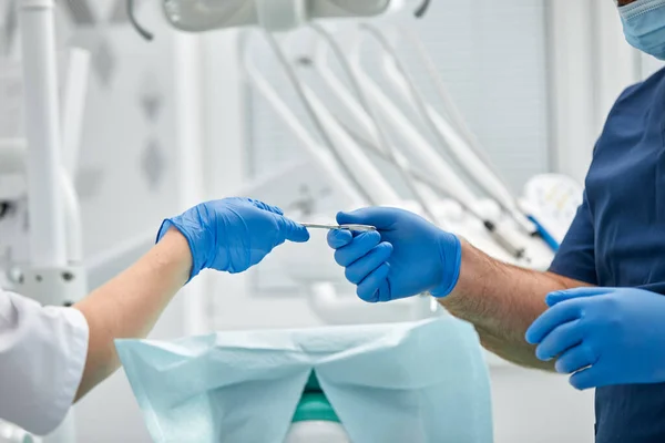Крупним планом руки стоматолога і медсестри-хірурга над операційною кімнатою під час операції з імплантації зубів — стокове фото