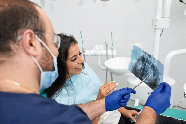 Mennesker, medicin, stomatologi og sundhedspleje koncept - glade mandlige tandlæge viser arbejdsplan til kvinde patient på tandklinik kontor - Stock-foto