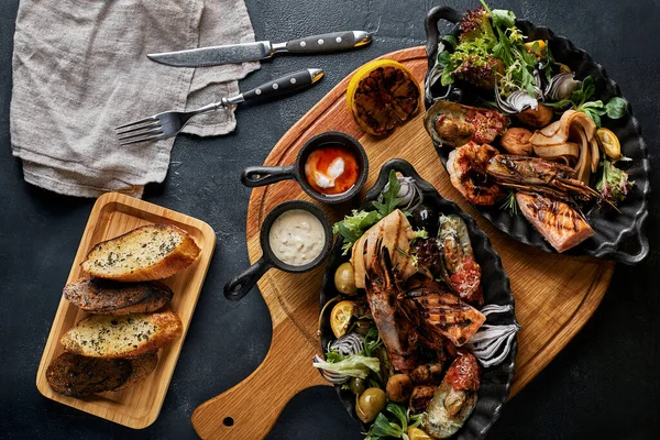 Plato de mariscos a la parrilla. Surtido de deliciosos mariscos a la parrilla con verduras. Bastardos mixtos a la parrilla con salsa de pimienta y verduras. Fondo negro — Foto de Stock