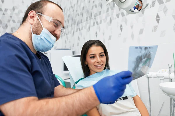 Menschen, Medizin, Stomatologie und Gesundheitskonzept - glücklicher Zahnarzt zeigt Patientin in Zahnarztpraxis Arbeitsplan — Stockfoto