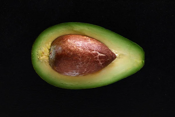 Makroaufnahme frischer Avocados, halbiert auf schwarzem Hintergrund — Stockfoto