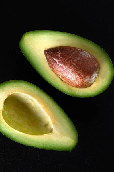 Makroaufnahme frischer Avocados, halbiert auf schwarzem Hintergrund — Stockfoto