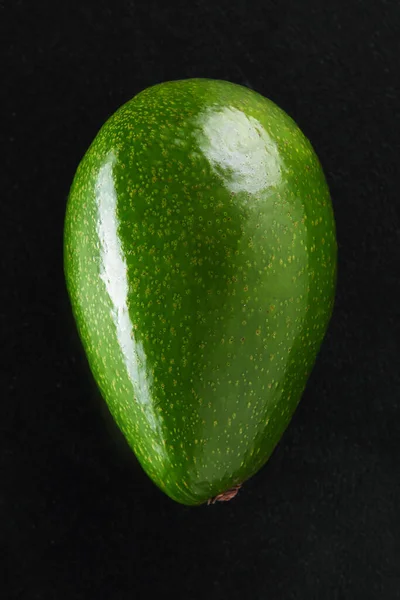 Aguacate fresco verde sobre fondo negro de cerca — Foto de Stock