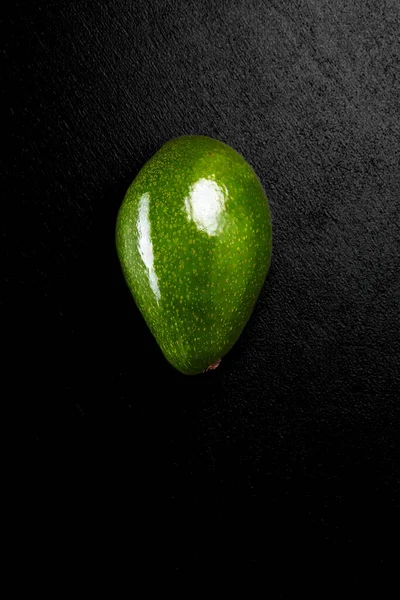 Зеленый свежий авокадо на черном фоне крупным планом — стоковое фото
