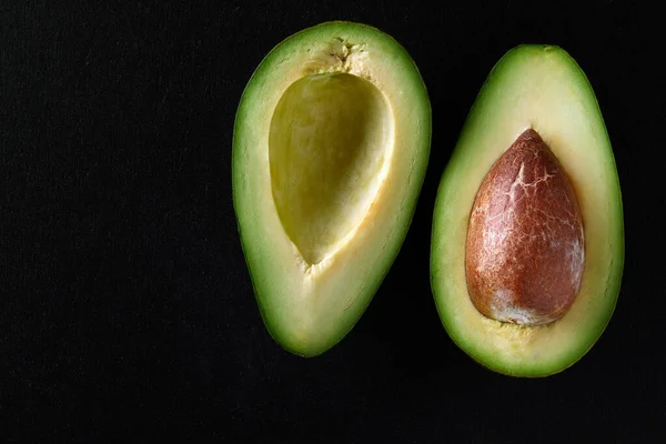 Makroaufnahme frischer Avocados, halbiert auf schwarzem Hintergrund — Stockfoto