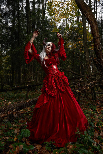 Stylish and fashionable model girl in the image of Maleficent posing among mystic forest - fairytale story, cosplay. Halloween.