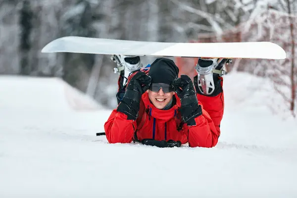 Hombre snowboarder en un traje rojo caminando sobre la colina nevada con snowboard, esquí y snowboard concepto — Foto de Stock