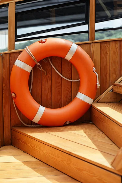Boya salvavidas naranja y cuerda vieja colgando en un barco — Foto de Stock