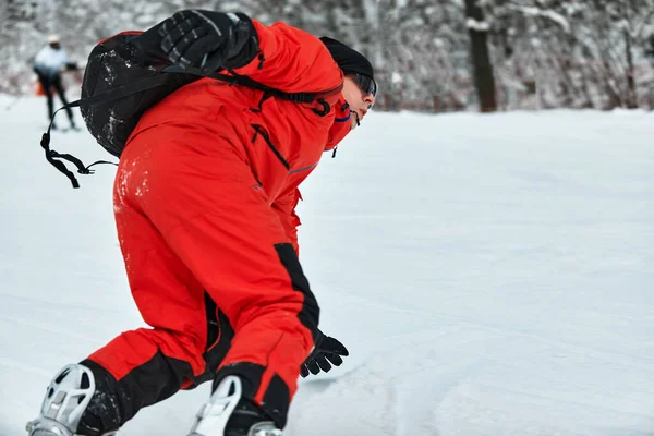 Männlicher Snowboarder im roten Anzug fährt mit Snowboard, Ski- und Snowboard-Konzept auf den verschneiten Hügel — Stockfoto