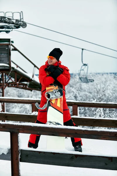 Homem snowboarder em um terno vermelho andando na colina nevada com snowboard, Esqui e snowboard conceito — Fotografia de Stock