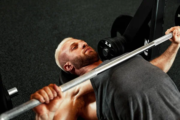 ジムでのバーベル付きの筋肉の男のトレーニングのクローズアップ肖像画。6パック、完璧な腹筋、肩、二足歩行、トリップと胸を持つ超能力ボディビルダーの運動マン — ストック写真