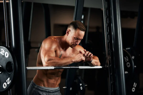 Retrato de close-up de um homem musculoso treino com barra no ginásio. Homem atlético fisiculturista brutal com seis maços, abdominais perfeitos, ombros, bíceps, tríceps e peito — Fotografia de Stock