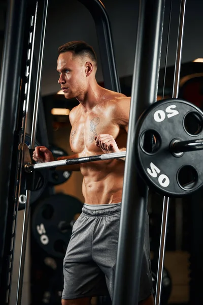 Nahaufnahme Porträt eines muskulösen Mannes beim Training mit der Langhantel im Fitnessstudio. Brutaler Bodybuilder athletischer Mann mit Sixpack, perfektem Bauch, Schultern, Bizeps, Trizeps und Brust — Stockfoto