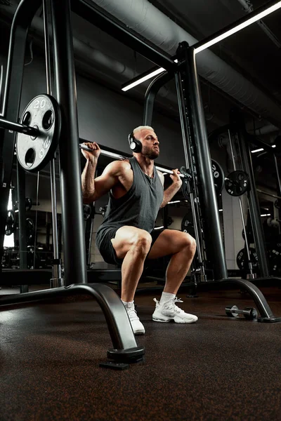 一个肌肉男带着杠铃在体育馆锻炼的特写镜头。健美健美运动员，六包，完美的腹肌、肩膀、二头肌、三头肌和胸部 — 图库照片