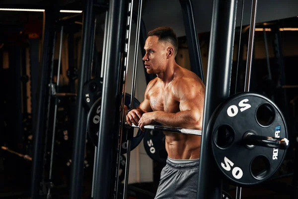 Крупним планом портрет м'язистого чоловіка тренування з барбелом в спортзалі. Жорстокий культурист спортсмен з шістьма пачками, досконалий абс, плечі, біцепси, трицепси і груди — стокове фото