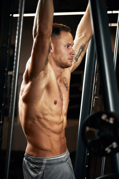 Close-up portret van een gespierde man workout met lange halter in de sportschool. Brutale bodybuilder atletische man met zes pack, perfecte buikspieren, schouders, biceps, triceps en borst — Stockfoto