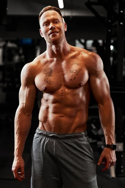 Zbliżenie portret muskularnego mężczyzny trenującego ze sztangą na siłowni. Brutalny kulturysta atletyczny mężczyzna z sześciopakiem, idealnym brzuchem, ramionami, bicepsami, tricepsami i klatką piersiową — Zdjęcie stockowe