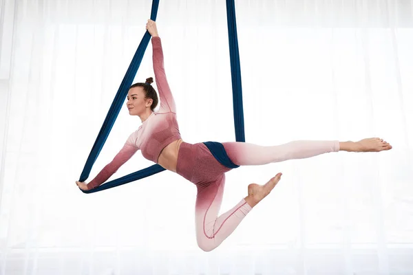 Geniş sağlık kulübünde panoramik pencereli anti-yerçekimi yogası yapan, üst ve tozluklu neşeli sportif kadın. — Stok fotoğraf