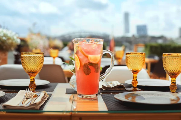 Limonada con naranjas en jarra con cubo de hielo sobre mesa blanca en restaurante — Foto de Stock