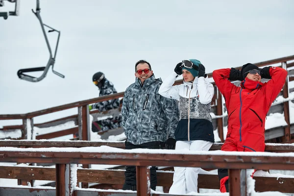 Eine Gruppe befreundeter Skifahrer am Berg ruht sich aus und trinkt Kaffee aus einer Thermoskanne im Hintergrund des Skilifts. — Stockfoto