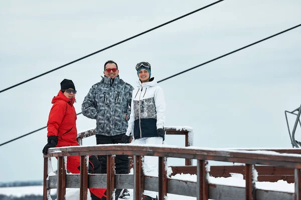 Eine Gruppe befreundeter Skifahrer am Berg ruht sich aus und trinkt Kaffee aus einer Thermoskanne im Hintergrund des Skilifts. — Stockfoto