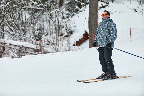 Un esquiador en chaqueta gris está montando cuesta abajo la pendiente en un día helado —  Fotos de Stock