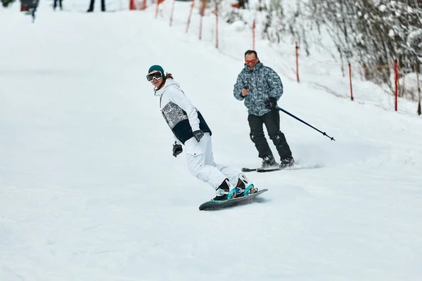 Κατεβαίνοντας σκιέρ. Snowboarders και σκιέρ βόλτα με το χιόνι στα βουνά. Κάτω βόλτα. Εποχή σκιέρ περιπέτειας. Χιονοδρομικά και Snowboarding Resorts. Εξοπλισμός για σκι και snowboard. Λάτρεις των χιονοδρομιών — Φωτογραφία Αρχείου