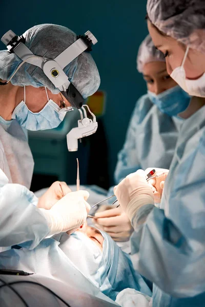 Los hombres de rinoplastia, los cirujanos con guantes de manos sostienen los instrumentos durante la cirugía de la nariz. Médico con guantes sostiene un instrumento médico durante la rinoplastia —  Fotos de Stock