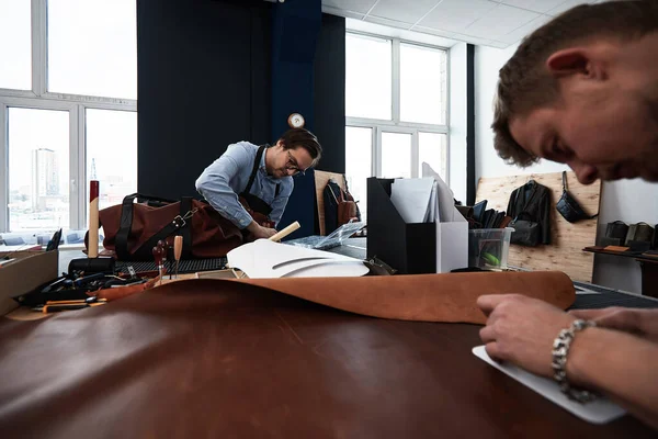 Artesãos de couro trabalhando fazendo medidas em padrões à mesa em estúdio oficina — Fotografia de Stock