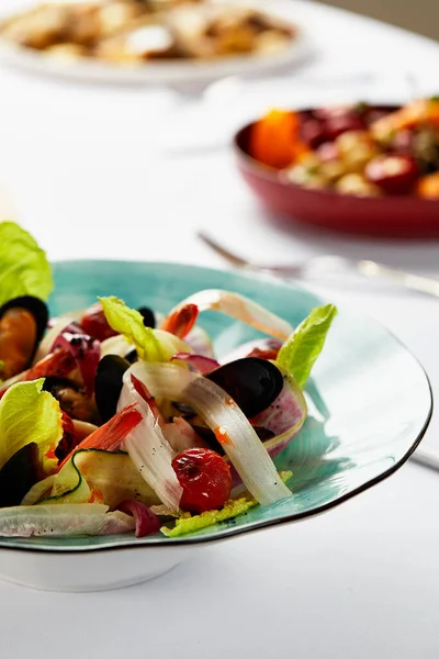 Muscheln Vongoli in einem Teller mit Salat, Miesmuscheln in einer Sauce mit Weißwein, Meeresfrüchte serviert vom Küchenchef, auf hellem Hintergrund, Nahaufnahme — Stockfoto