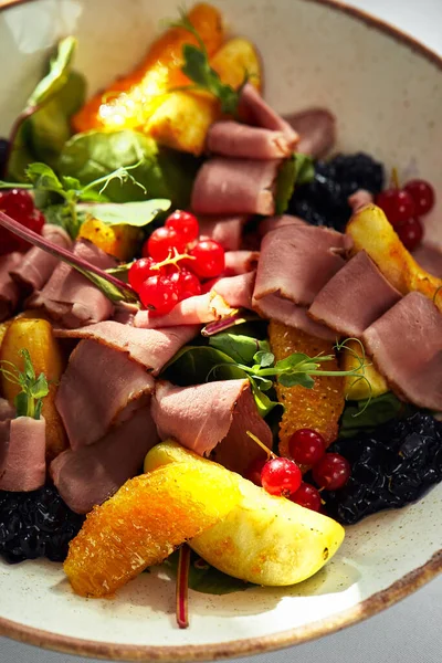 Duck breast salad. Cold smoked duck breast in salad with oranges and apples and red berries
